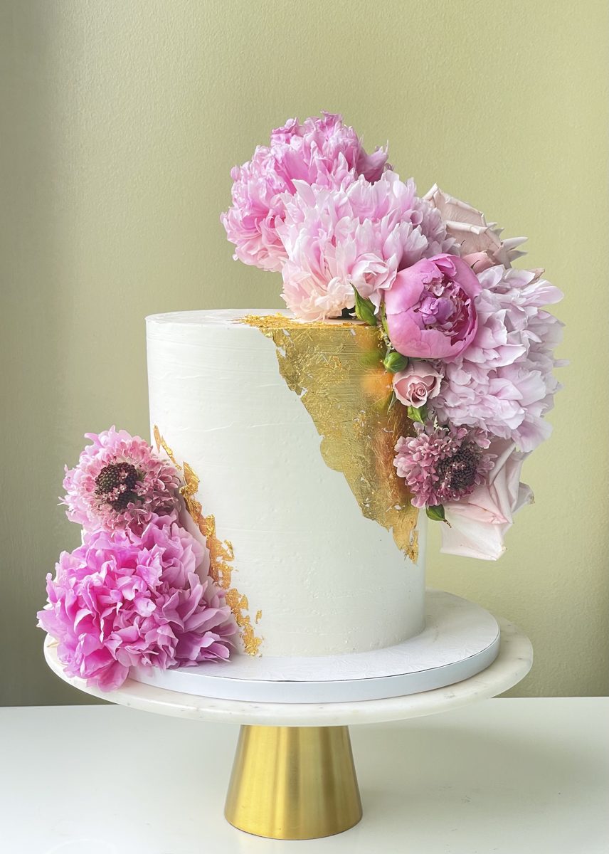 Pink anniversary cake with magenta florals and a gold geode