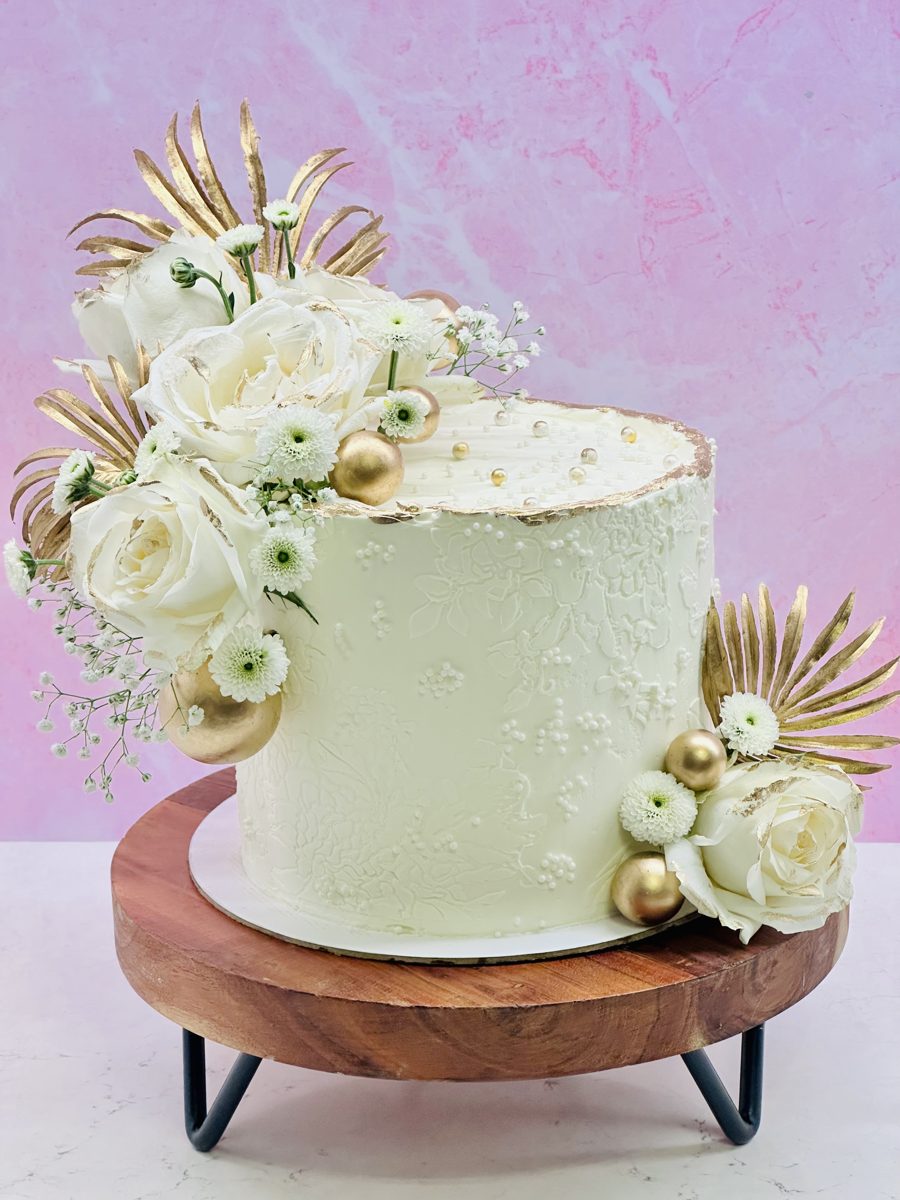 White textured wedding cake with fresh white roses and gold
