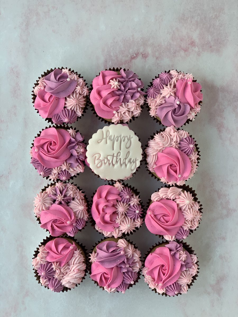 Pink rose and dahlia buttercream cupcakes on a display board