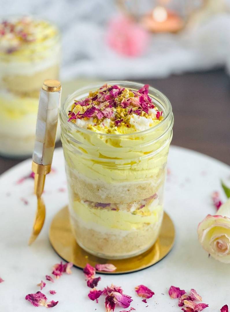 Pistachio-rose jar dessert with petals and a gold spoon